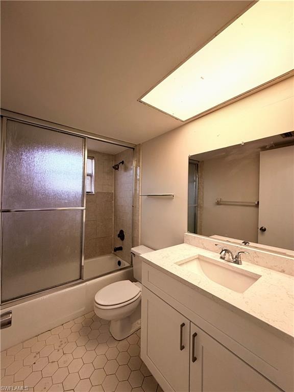 Bathroom featuring a white vanity with a light-colored countertop and integrated sink, a rectangular mirror, and a bathtub with sliding glass doors and tiled surround