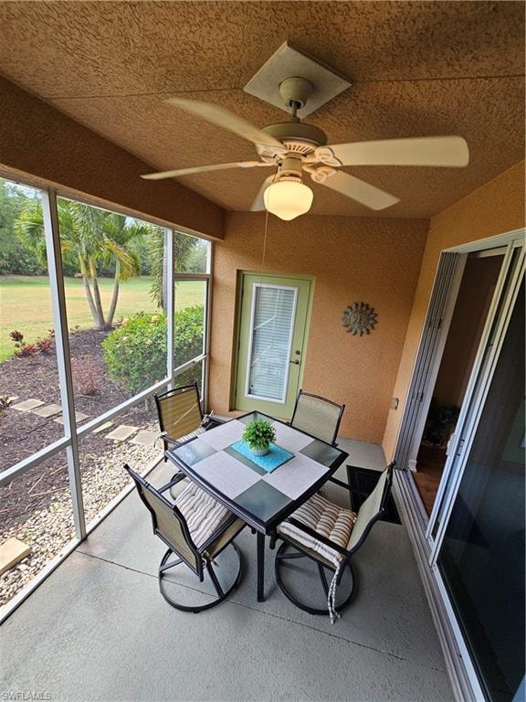 Sunroom / solarium featuring a ceiling fan, plenty of natural light, and outdoor dining area