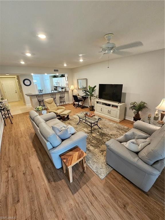Living room featuring light wood-style floors, a ceiling fan, and recessed lighting
