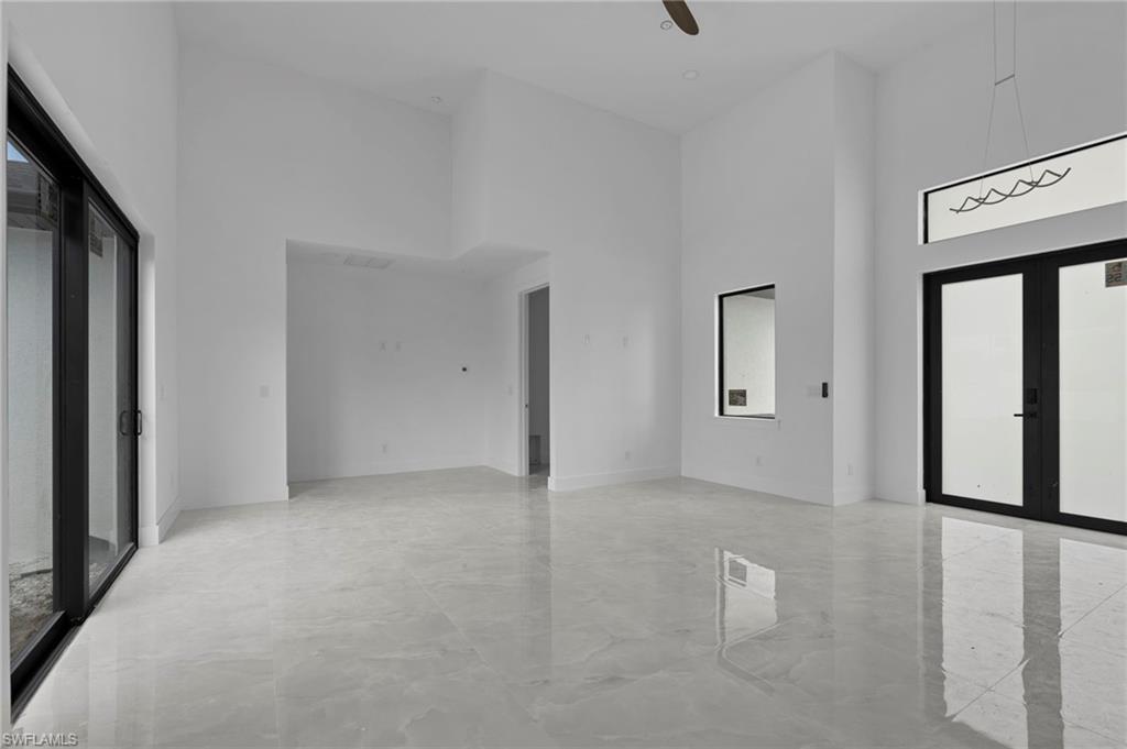 Empty room featuring french doors, a towering ceiling, and ceiling fan