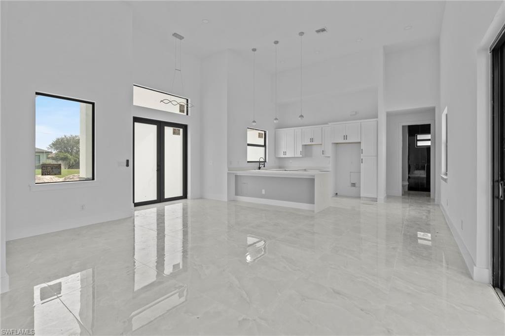 Unfurnished living room with sink, a towering ceiling, and french doors