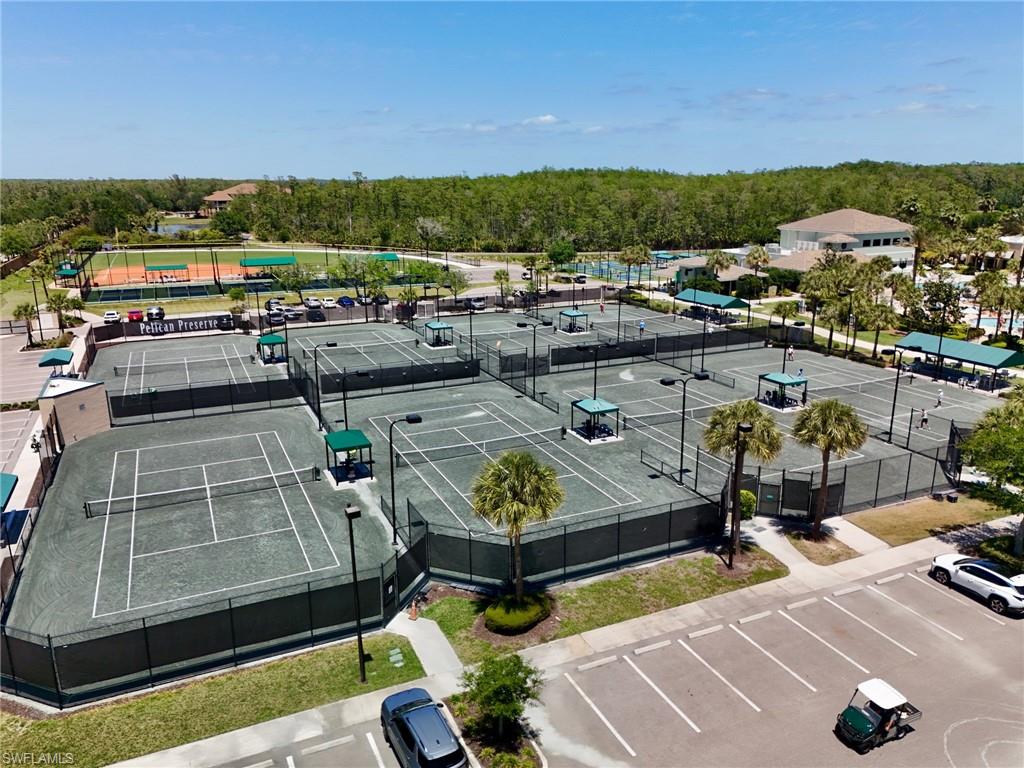Extensive tennis facilities featuring multiple hard courts, clay courts, shaded seating areas, and perimeter fencing