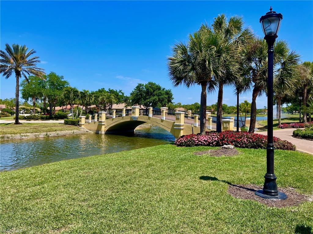 Beautifully landscaped grounds featuring pedestrian bridges over waterways, mature palm trees, and paved walking and cart paths