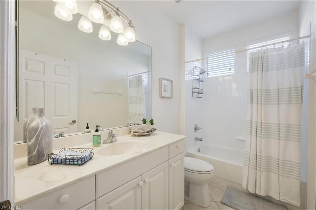 Bathroom with shower / tub combo with curtain, vanity, and light tile patterned floors