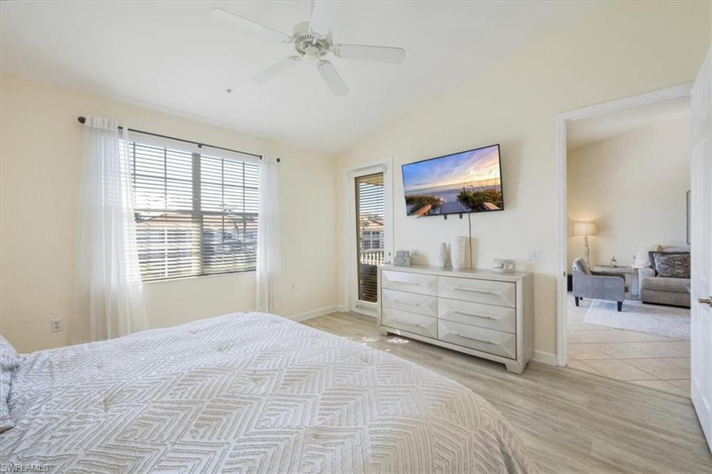 Bedroom with lofted ceiling, light wood-style floors, ceiling fan, and access to exterior