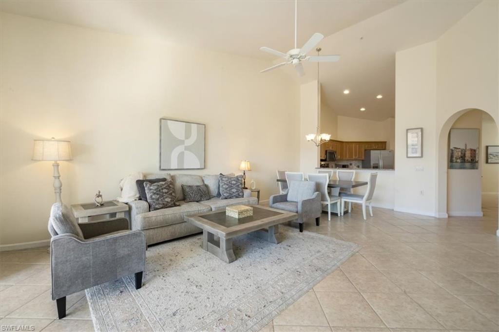 Living room featuring high vaulted ceiling, arched walkways, a ceiling fan, and light tile patterned floors