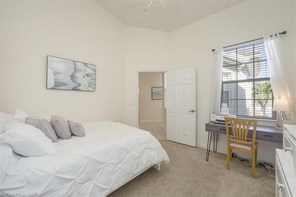 Bedroom with light carpet, a high ceiling, and a ceiling fan
