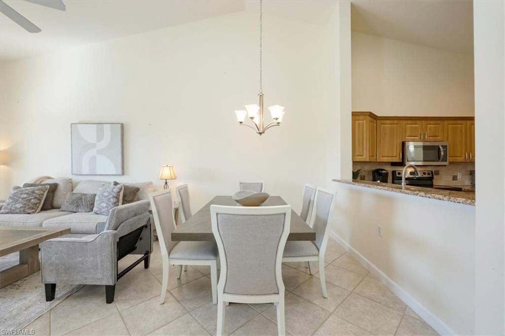 Dining area featuring a chandelier, light tile patterned flooring, and high vaulted ceiling