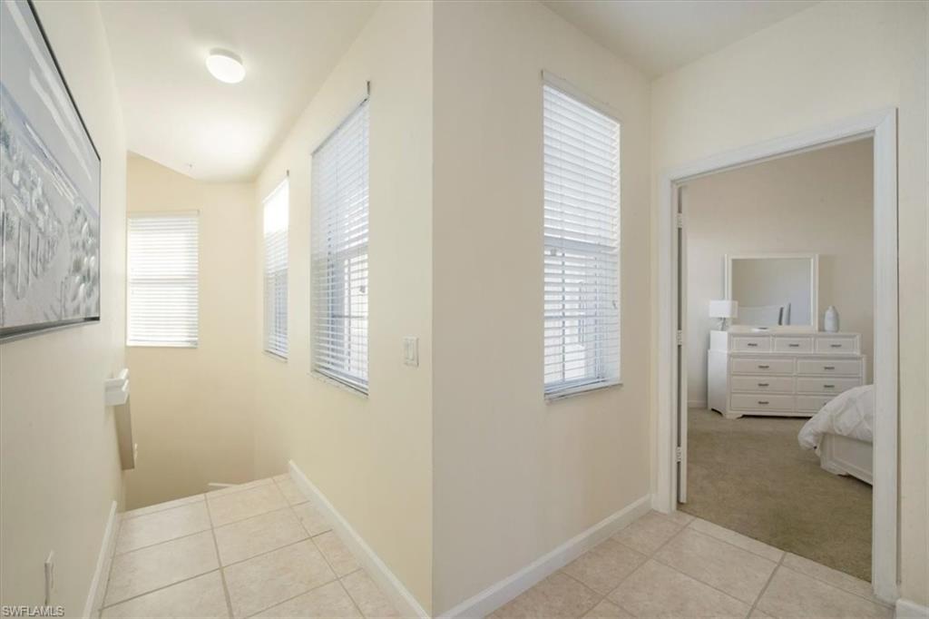Hallway featuring light tile patterned floors, plenty of natural light, and light carpet