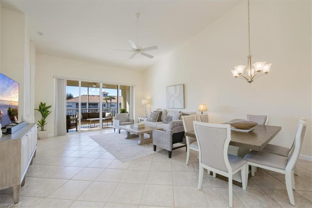 Living room with high vaulted ceiling, a chandelier, a ceiling fan, and light tile patterned floors