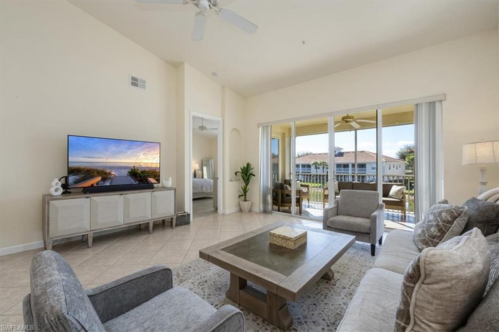 Living room with light tile patterned floors and high vaulted ceiling