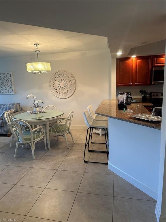 Kitchen featuring kitchen peninsula, light tile patterned floors, range, and decorative light fixtures
