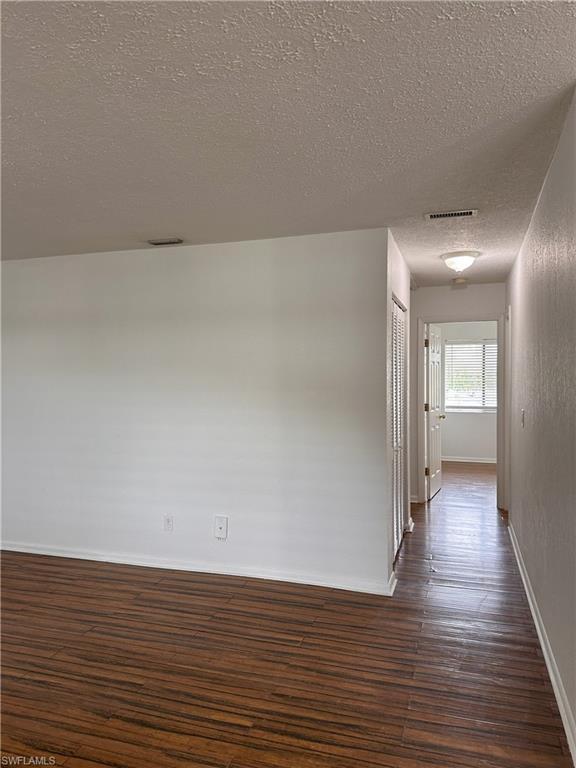 Corridor with dark wood-style flooring and a textured ceiling