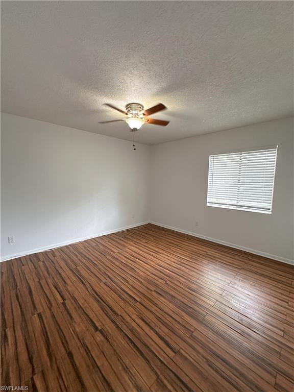 Spare room featuring dark wood finished floors, a textured ceiling, and ceiling fan