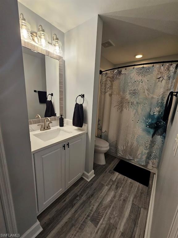 Bathroom featuring toilet, wood finished floors, vanity, and a shower with shower curtain