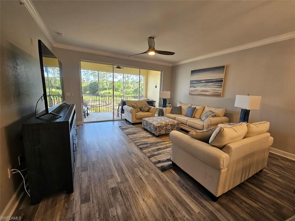 Living area with ornamental molding, ceiling fan, dark wood-style floors, and baseboards