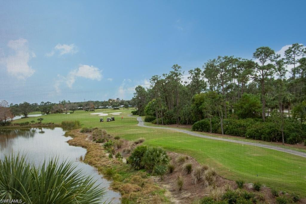 View of community with golf course view, a yard, and a water view