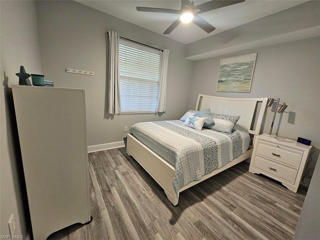 Bedroom with dark wood-style flooring, baseboards, and a ceiling fan