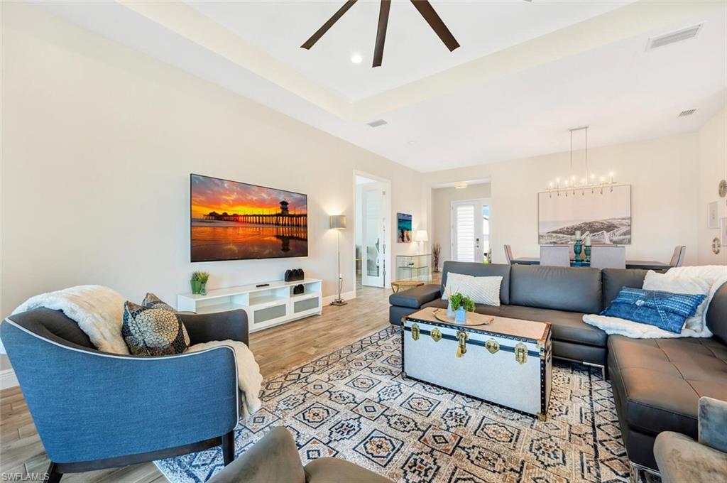 Living room featuring ceiling fan with notable chandelier and light hardwood / wood-style flooring