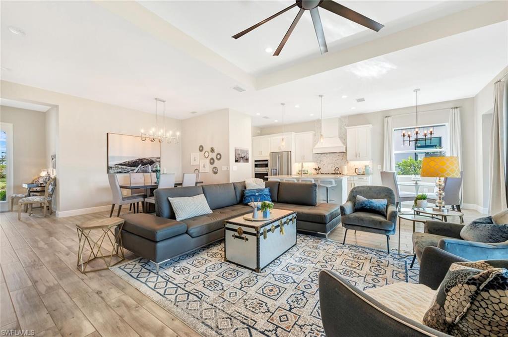 Living room featuring ceiling fan with notable chandelier and light wood-type flooring