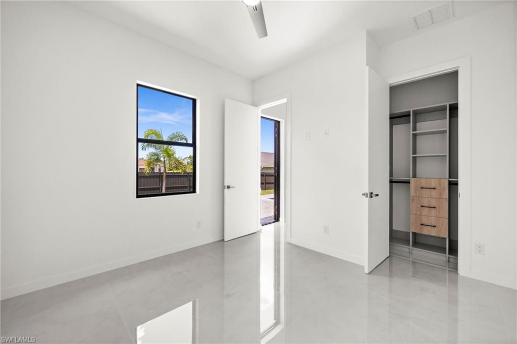 Bright room featuring a black-framed window, sleek reflective flooring, and a modern ceiling fan