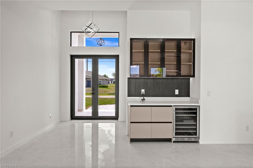 Entry foyer featuring double glass-panel doors, transom window, and a modern geometric pendant light