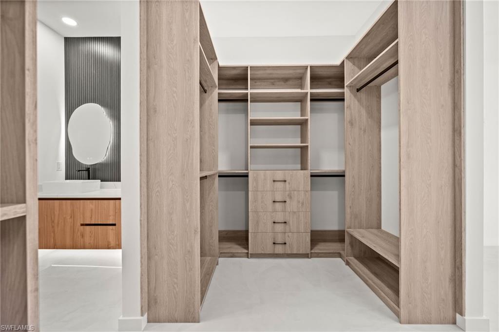 Spacious walk-in closet featuring extensive built-in shelving, hanging rods, and integrated drawer storage