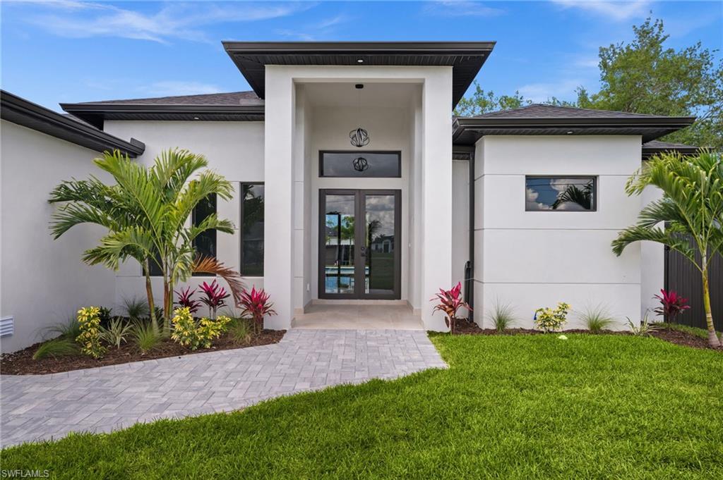 Modern architectural facade featuring a prominent entryway, double glass panel doors, and a paver walkway