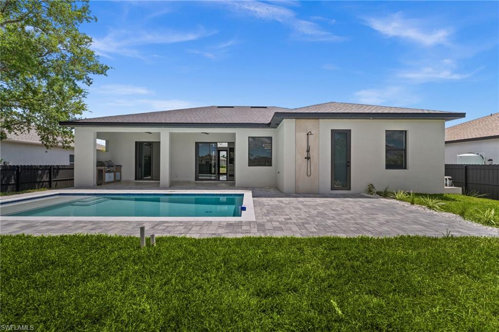 Expansive backyard featuring a rectangular swimming pool, paver patio, and covered lanai