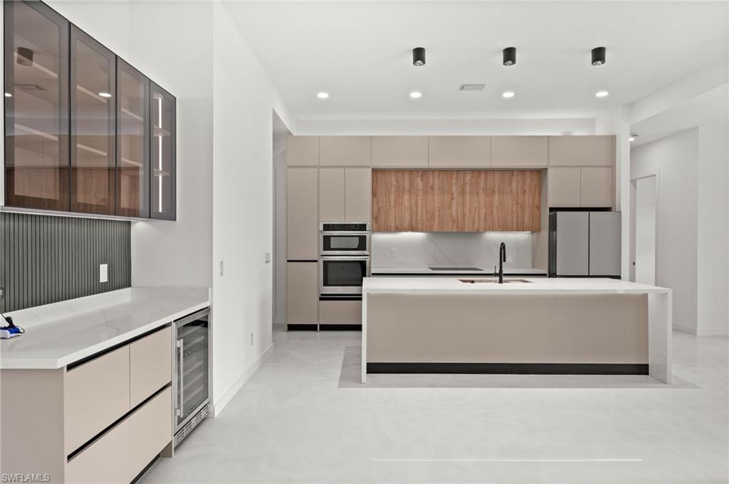 Modern kitchen featuring a large central island with an integrated sink and black faucet