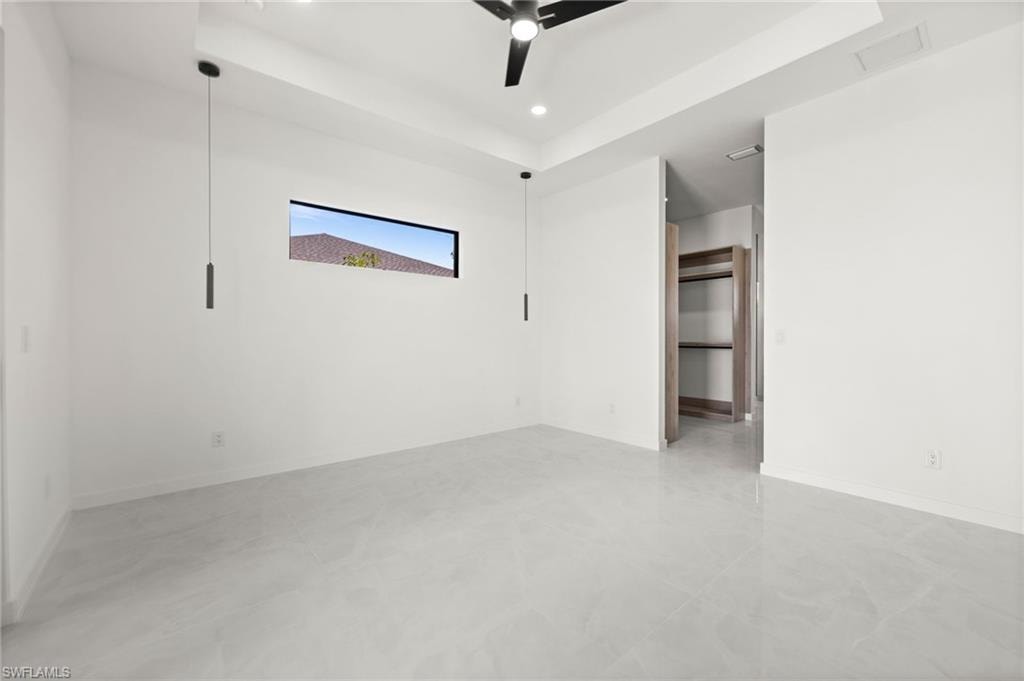 Spacious interior featuring light gray tile flooring, crisp white walls, and a recessed ceiling