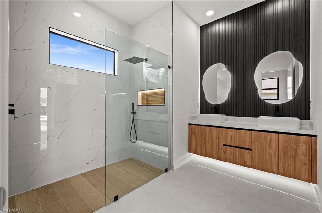 Contemporary bathroom featuring a spacious glass-enclosed shower with large format marble-look wall tiles and a horizontal window