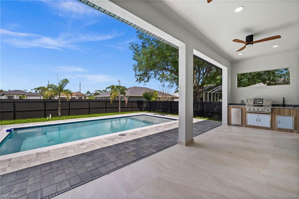 Expansive outdoor living area featuring a rectangular swimming pool, paver deck, and a covered patio