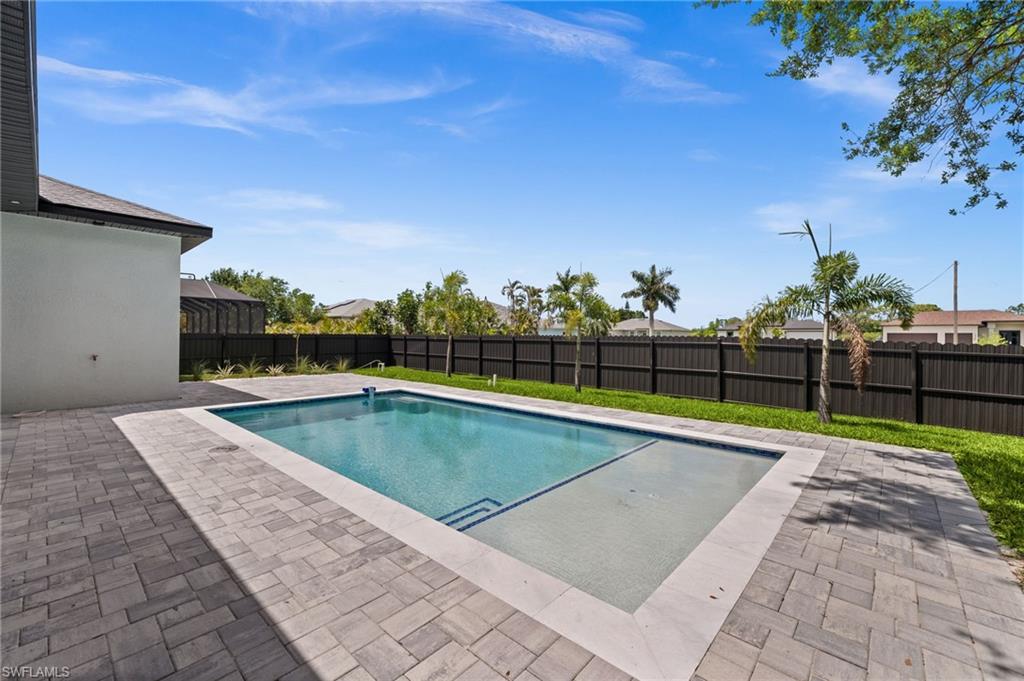Private backyard oasis featuring a rectangular swimming pool with integrated steps, surrounded by extensive paver decking