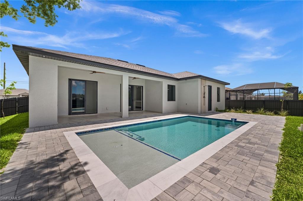 Rectangular swimming pool with integrated spa, bordered by light-toned coping and a paver patio