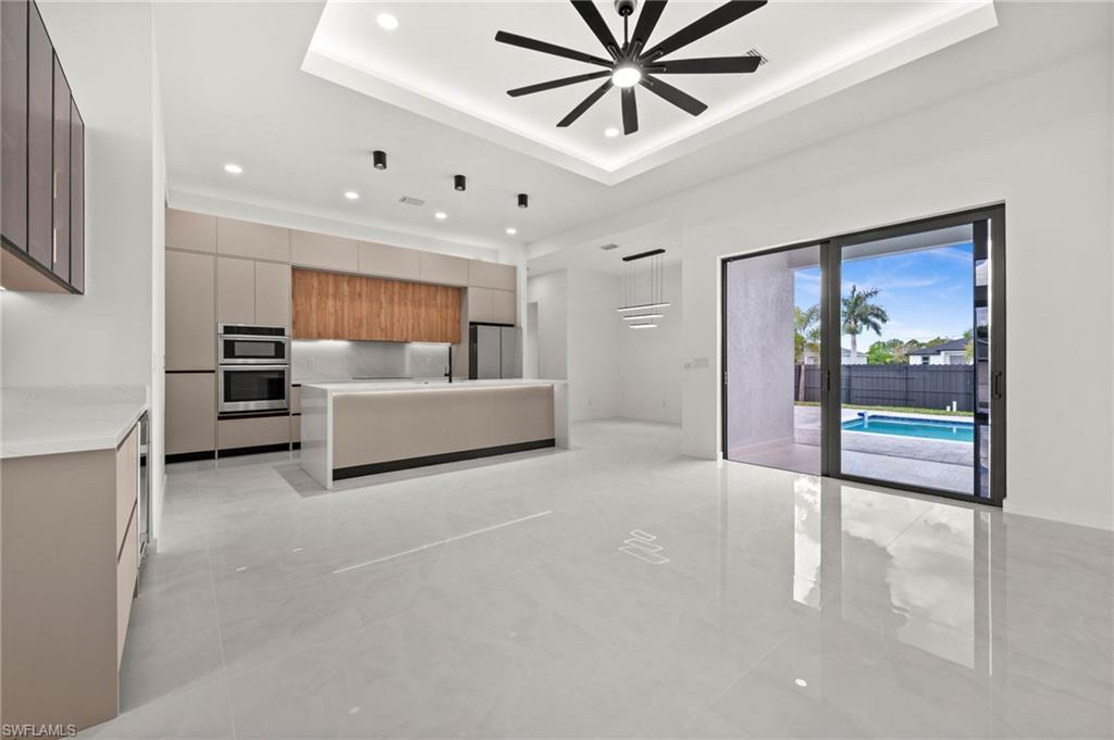 Spacious open-concept kitchen featuring a large central island, integrated stainless steel appliances, and sleek flat-panel cabinetry
