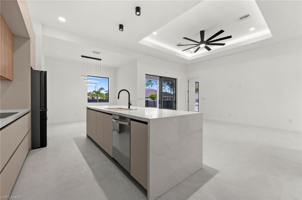 Modern kitchen featuring a large waterfall-edge island with an integrated dishwasher, a black gooseneck faucet, and quartz countertops