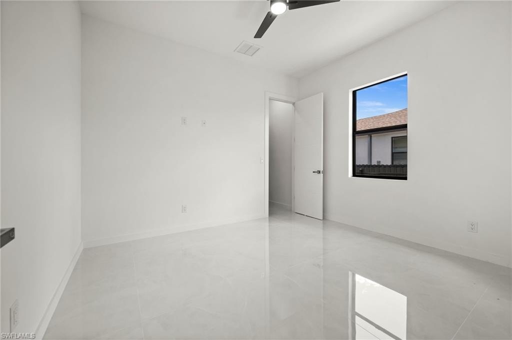 Bright room featuring a ceiling fan with light, a single window, and a door with modern hardware