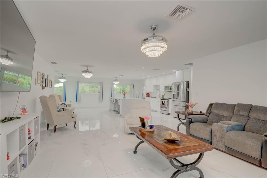 Open-concept living space featuring high-gloss tile flooring, recessed lighting, and multiple crystal-tiered ceiling fixtures