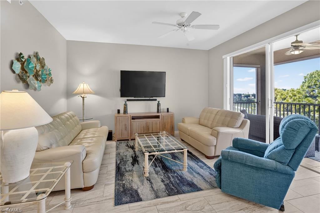 Living area featuring tile flooring, neutral wall tones, a ceiling fan, and sliding glass doors leading to a private outdoor space with a metal railing