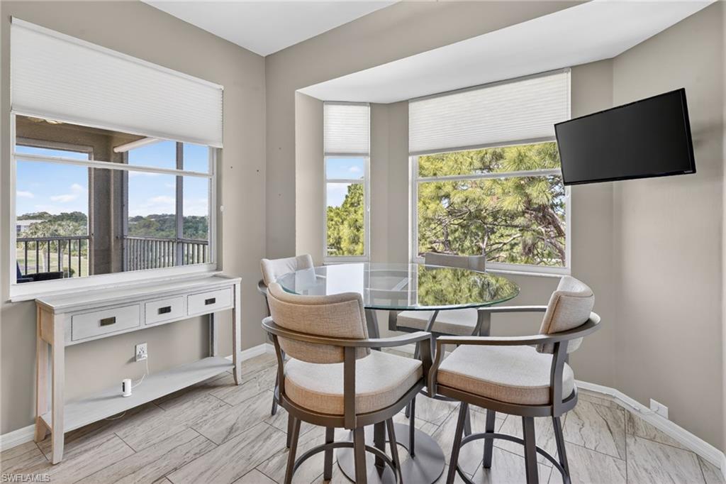 Dining area featuring a bay window with ample natural light, a wall-mounted television, and wood-finish flooring