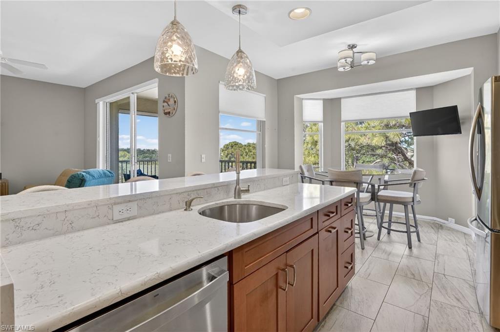 Kitchen featuring an island with white stone countertops, a stainless steel sink, and a built-in dishwasher