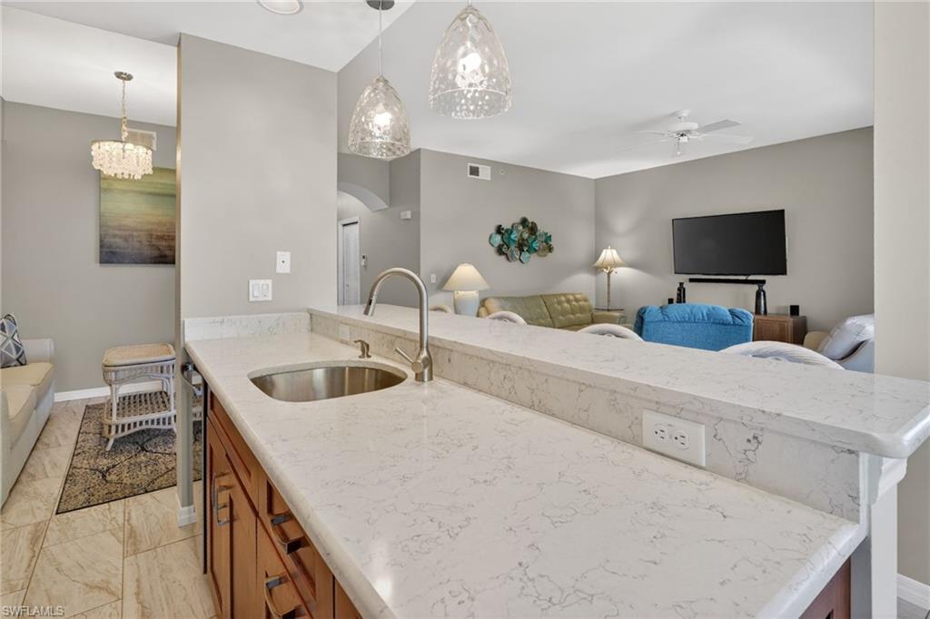 Kitchenette featuring a stainless steel sink, a gooseneck faucet, and light-toned countertops with a subtle vein pattern