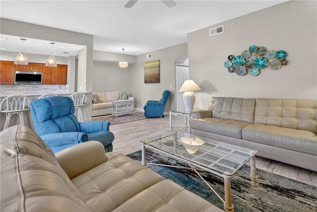 Open-concept living area featuring light-toned flooring, a kitchen pass-through with breakfast bar, and recessed lighting