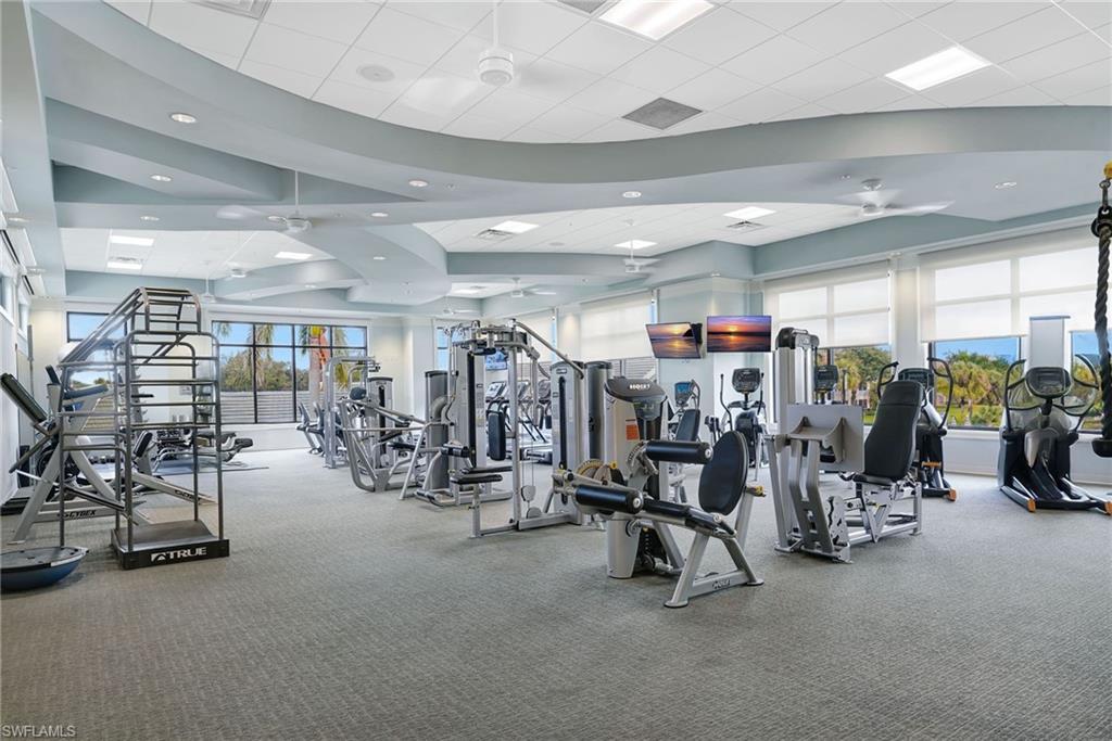 Spacious fitness center featuring an array of exercise equipment, large windows, recessed lighting, ceiling fans, and a light-colored carpeted floor