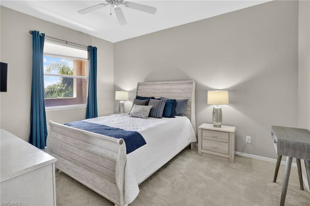 Carpeted room featuring a window with blue drapes, a ceiling fan, and light gray wall paint