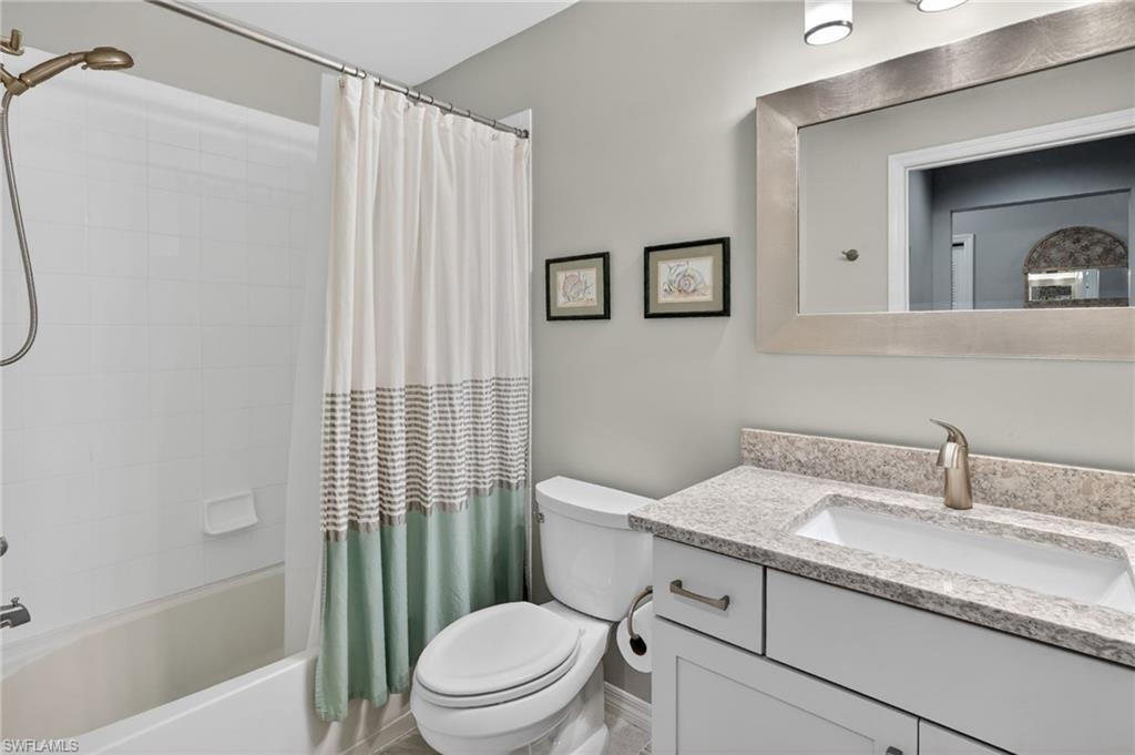 Bathroom featuring a white vanity with brushed nickel hardware, light-toned countertop, integrated sink, and framed mirror