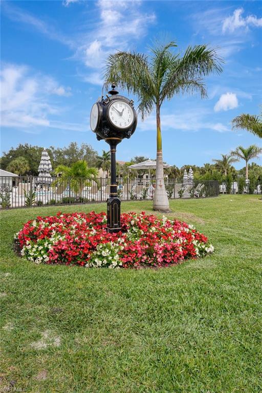Decorative street clock feature with a vibrant flower bed of red and white blooms