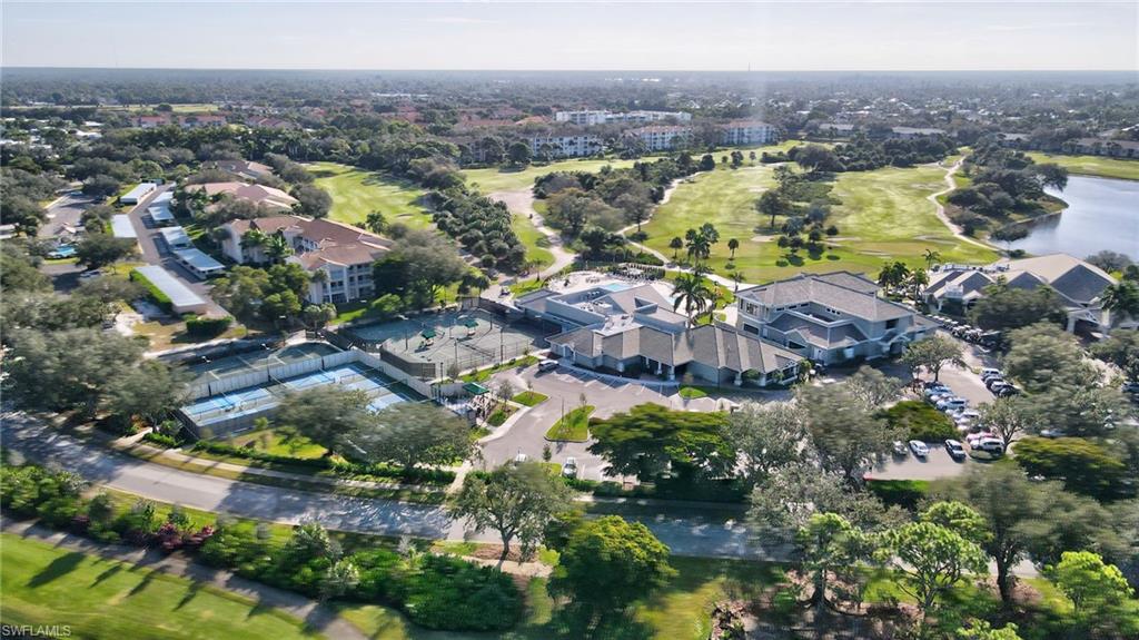 Aerial perspective showcasing a residential community with a large golf course, multiple tennis courts, and a central clubhouse structure