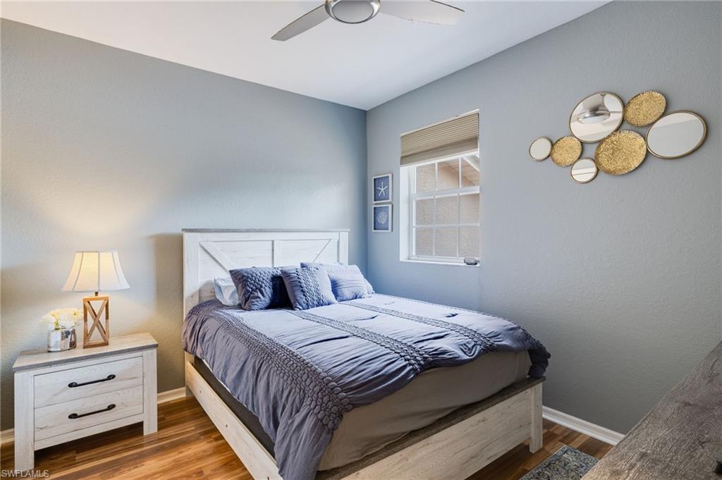Bedroom featuring wood-finish flooring, a double-paned window, and a ceiling fan